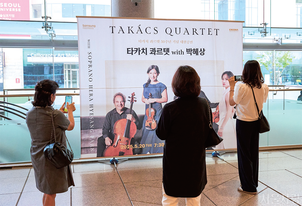 예술의전당 공연 현수막에 소개된 아티스트를 휴대폰으로 촬영하는 클래식 팬들.